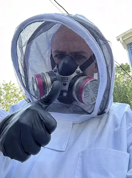 Person in protective gear with a respirator giving a thumbs up
